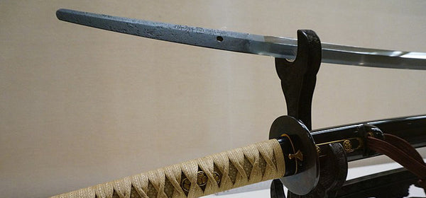 Alt-text: A full-tang katana on a display stand. Image on Wikimedia Commons.